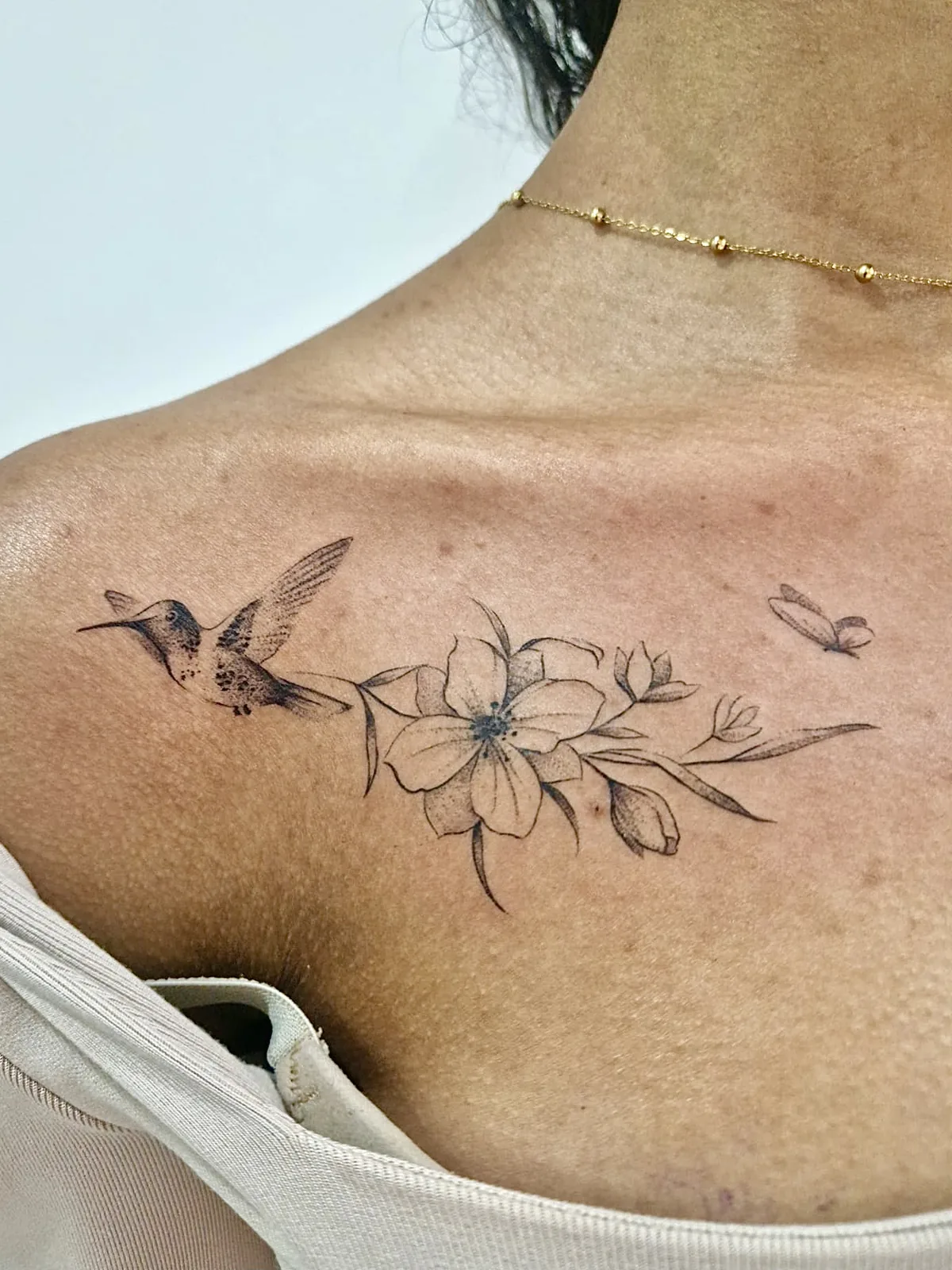 Tatouage colibri fleur fineline sur clavicule réalisé au studio Showtime Tattoo Paris Châtelet