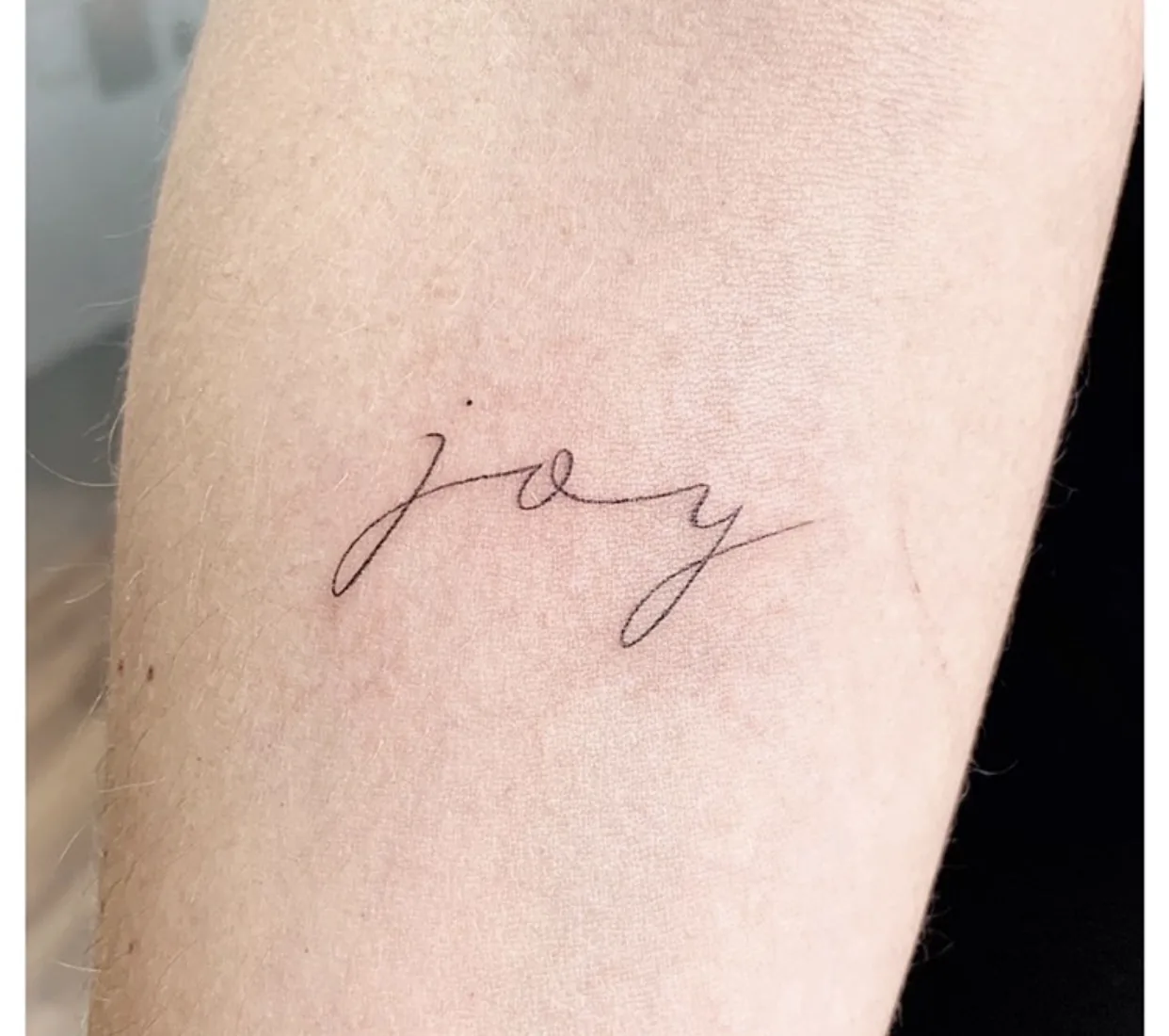 Tatouage lettrage Joy fineline minimaliste très fin réalisé chez Showtime Tattoo Paris Châtelet